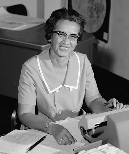 Katherine Johnson seated at a calculator.